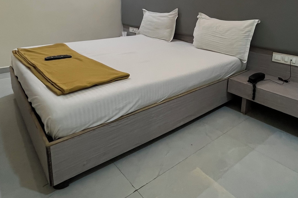 Une chambre d’hôtel moderne avec un grand lit, une table de chevet, une commode et un ventilateur de plafond.
