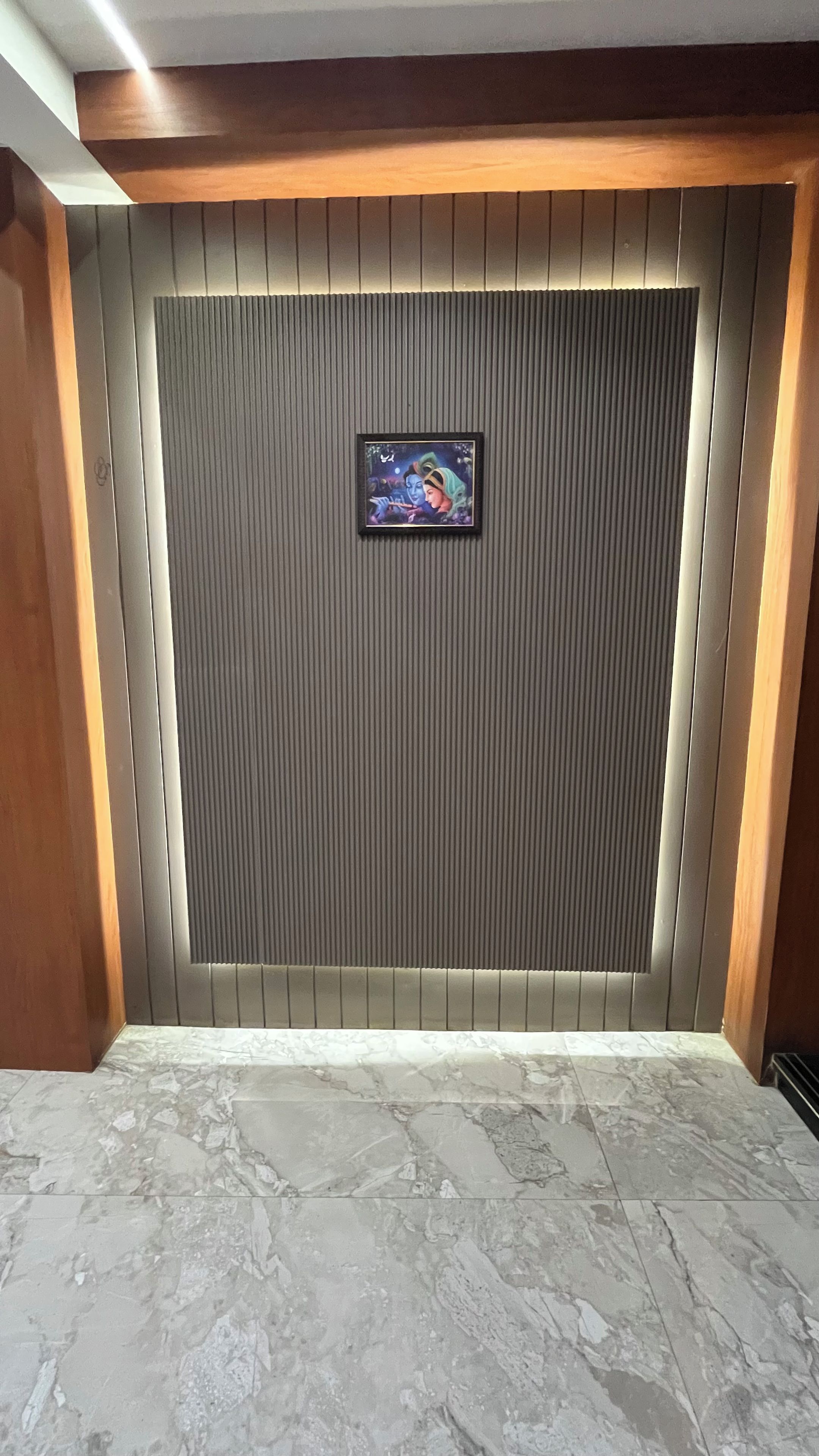 A room with a marble floor, a framed artwork on a textured wall, and wooden paneling.