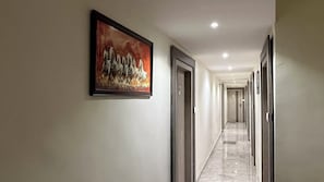 Passadís amb portes a ambdós costats, una obra d'art emmarcada a la paret esquerra i un sostre amb il·luminació empotrada.