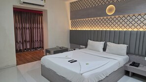 Une chambre d’hôtel moderne avec un grand lit, des tables de chevet, un bureau et un plafond décoré de motifs.