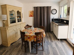 Une cuisine avec une table à manger, des chaises, un buffet, une horloge et une fenêtre.