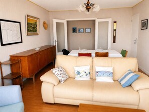 A living room with a beige sofa, a wooden cabinet, and a dining table with chairs. - All on foot • Private parking   • 2 bedrooms (Le Pouliguen)
