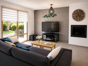 A modern living room with a sofa, coffee table, TV, fireplace, and decorative wall art. - Beach within walking distance • Master bedroom • 8 people (Pornichet)
