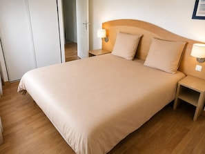 A neatly made bed with a wooden headboard, two bedside tables with lamps, and a wooden floor. - Beach within walking distance • Master bedroom • 8 people (Pornichet)