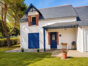 A two-story house with a blue door and a number '1' sign, surrounded by a well-maintained lawn and potted plants. - Beach within walking distance • Master bedroom • 8 people (Pornichet)