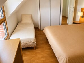 Ein Schlafzimmer mit zwei Betten, Holzboden, einem Fenster und einer Tür.