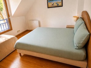 Een slaapkamer met een bed, nachtkastje, lamp en raam.