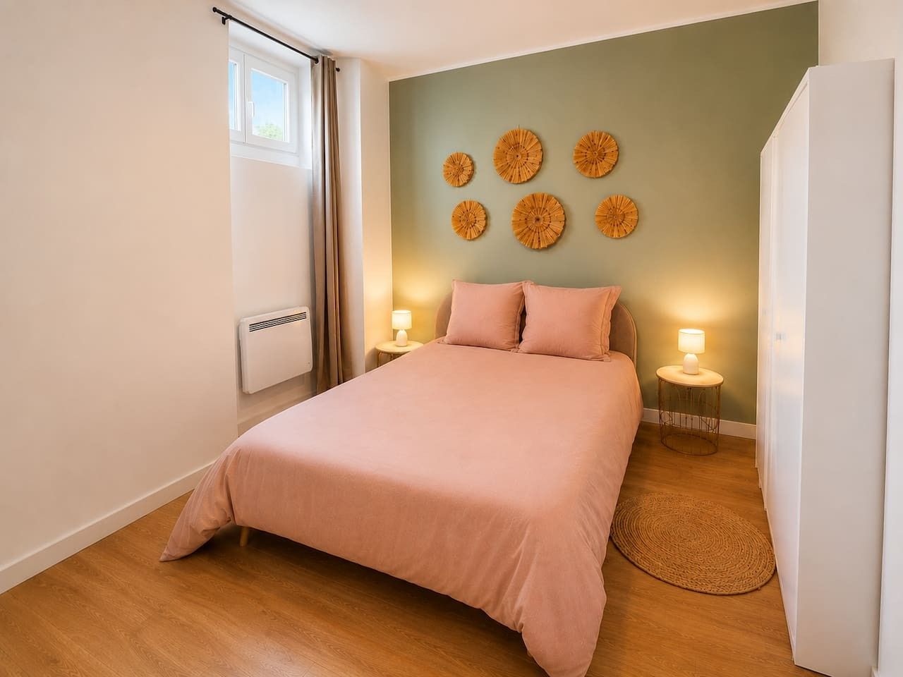 A bedroom with a bed, bedside lamps, a radiator, and wall decor.