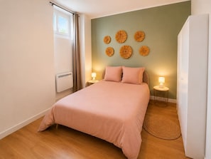 Ein Schlafzimmer mit einem Bett, Nachttischlampen, einem Heizkörper und Wanddekoration.