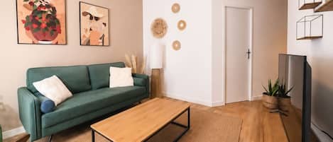 A living room with a green sofa, a wooden coffee table, and a television.