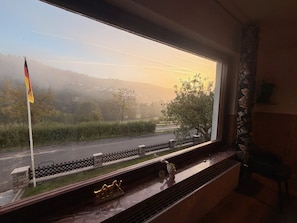 A room with a large window overlooking a road and a flag. - Spessart Dream: 17 guests, 5 bedrooms, foosball, and a view of the valley in the nature park (Sinntal)