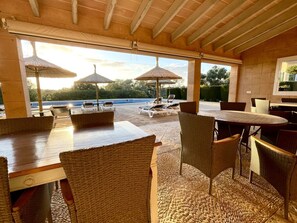 An outdoor patio area with wicker furniture, umbrellas, and a view of a swimming pool. - Holiday Home With 2 Bedrooms (Campos)