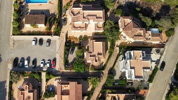 An aerial view of a residential area with multiple houses, a swimming pool, and a parking lot.