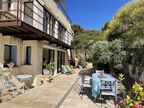A building with a balcony, outdoor seating, and potted plants. - Villa Grand Bleu (La Seyne-sur-Mer)