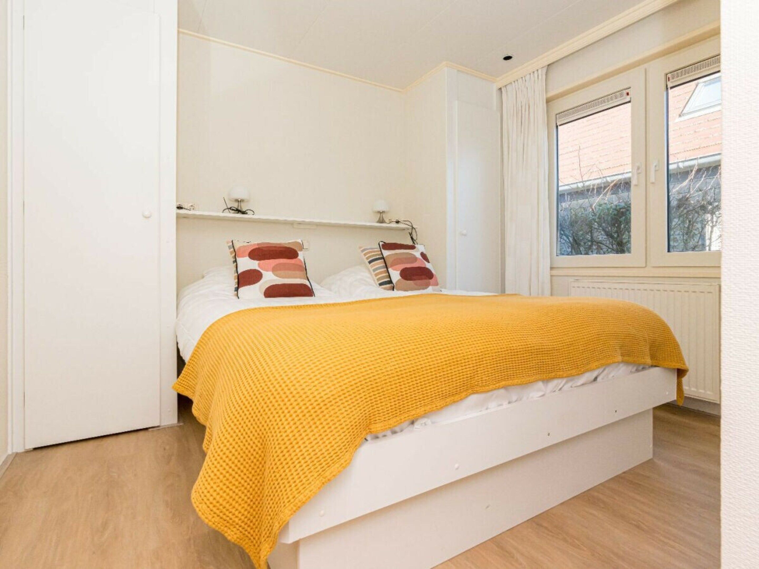 A bedroom with a bed, a window, and a white wall.