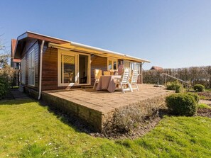 A wooden house with a patio, a table, and two chairs. - Cabin With 2 Bedrooms (Burgh-Haamstede)