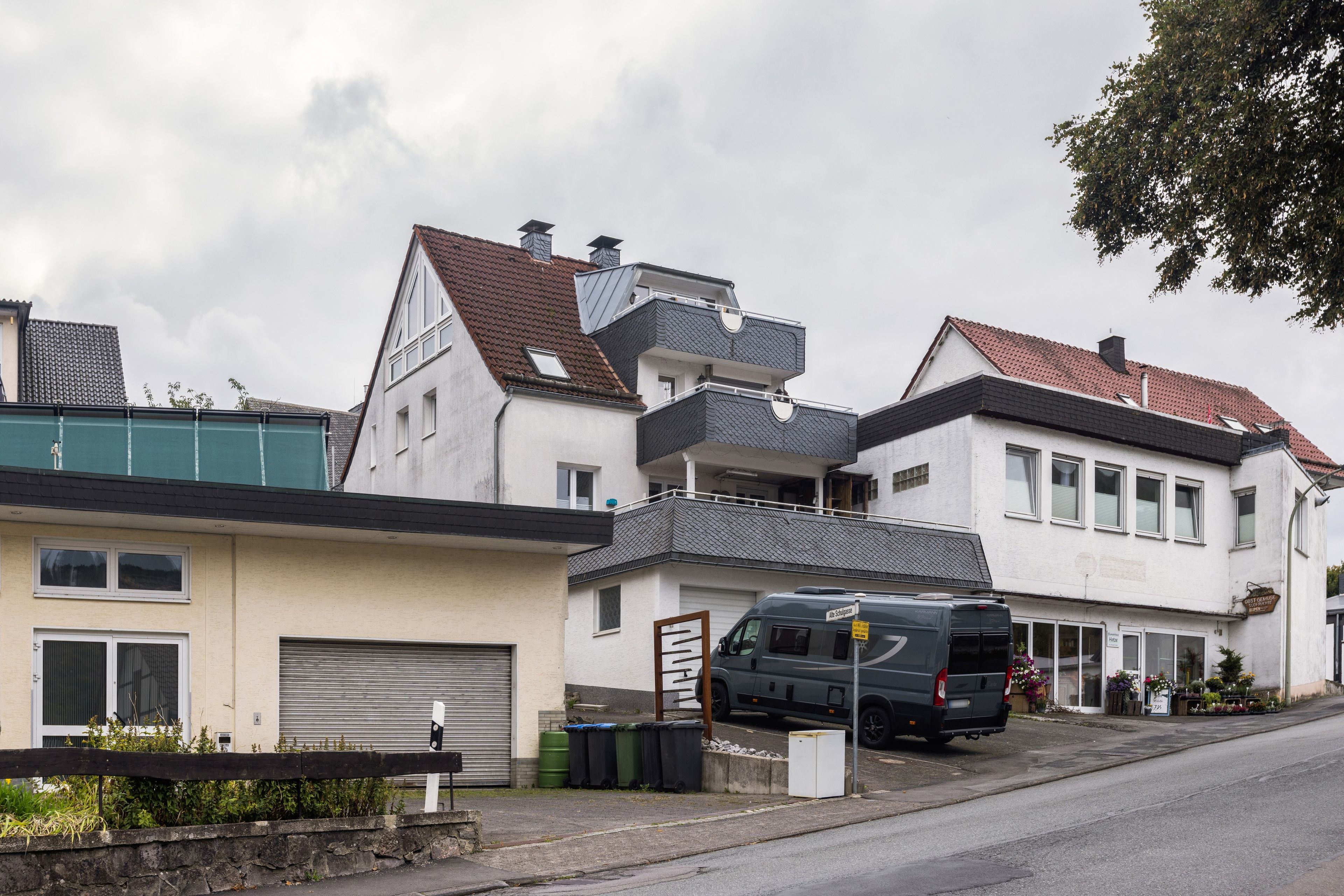 Eine Wohnstraße mit Häusern, einem Lieferwagen und einer geschlossenen Garagentür.
