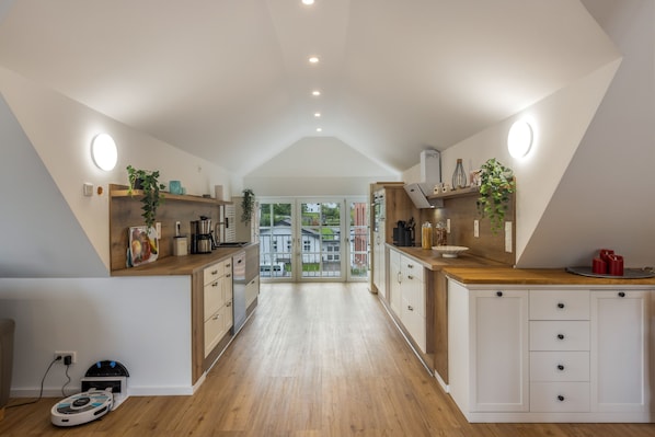 A modern kitchen with wooden cabinets, a central island, and a view to the outside.