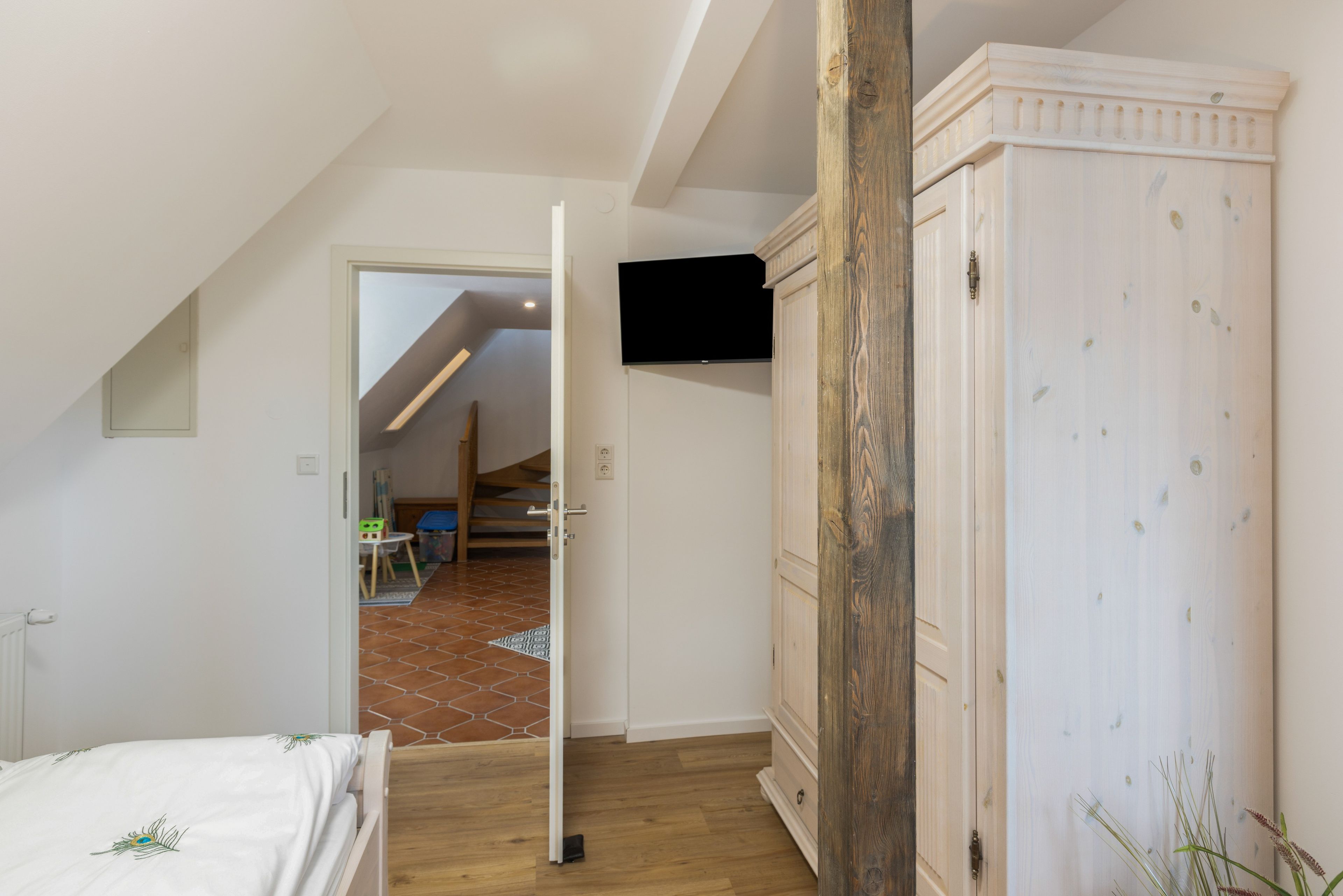 Une chambre à coucher comprenant un lit, une armoire et un téléviseur fixé au mur.