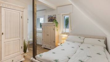 Une chambre à coucher avec un lit, une armoire, un miroir, une fenêtre et une plante.