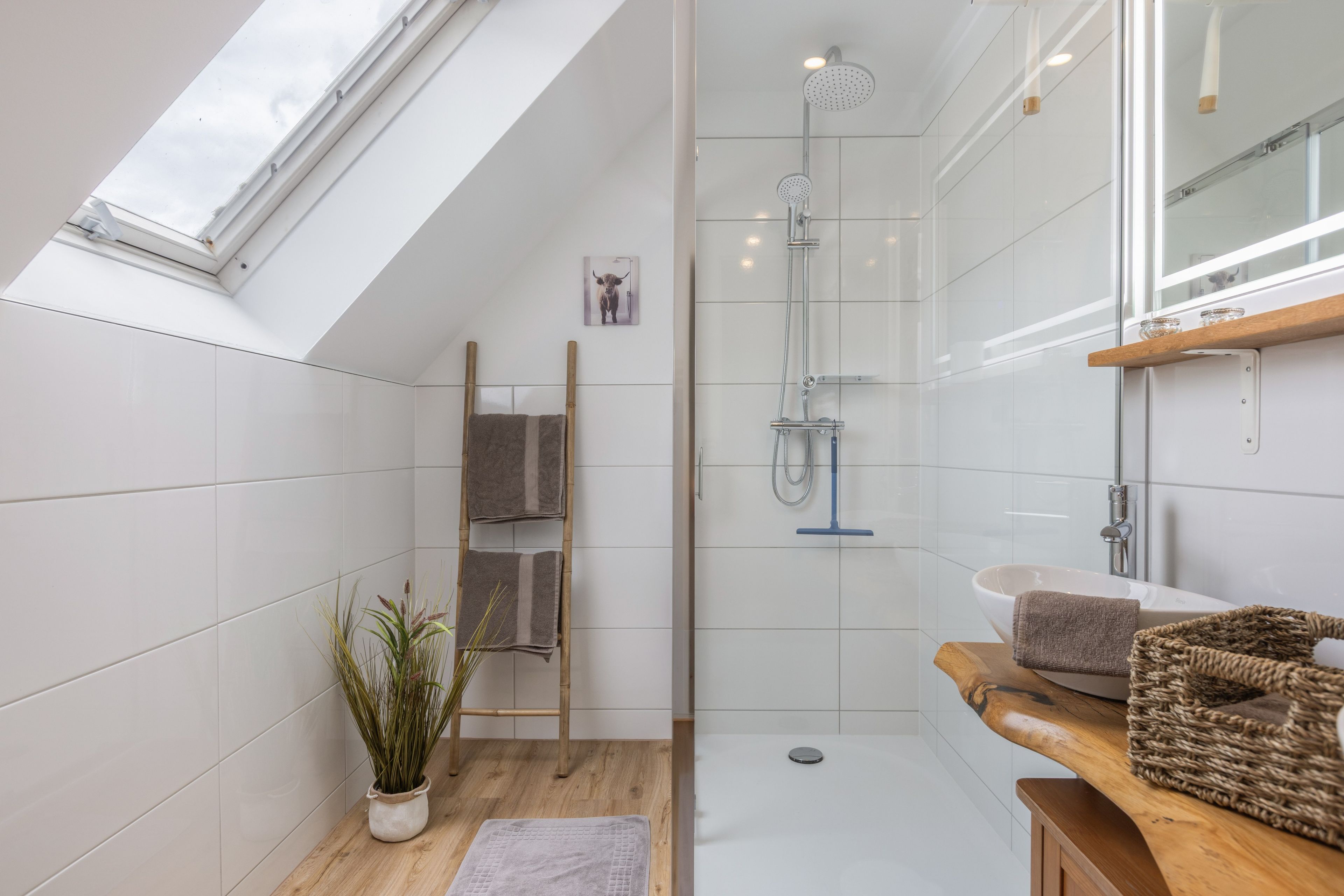 Ein modernes Badezimmer mit Dachfenster, Dusche, Waschbecken und einem Holzregal.