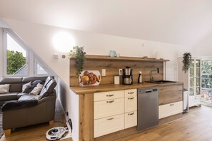 Een moderne keuken met houten kastjes, een ingebouwde vaatwasser en een fruitschaal op het aanrecht.