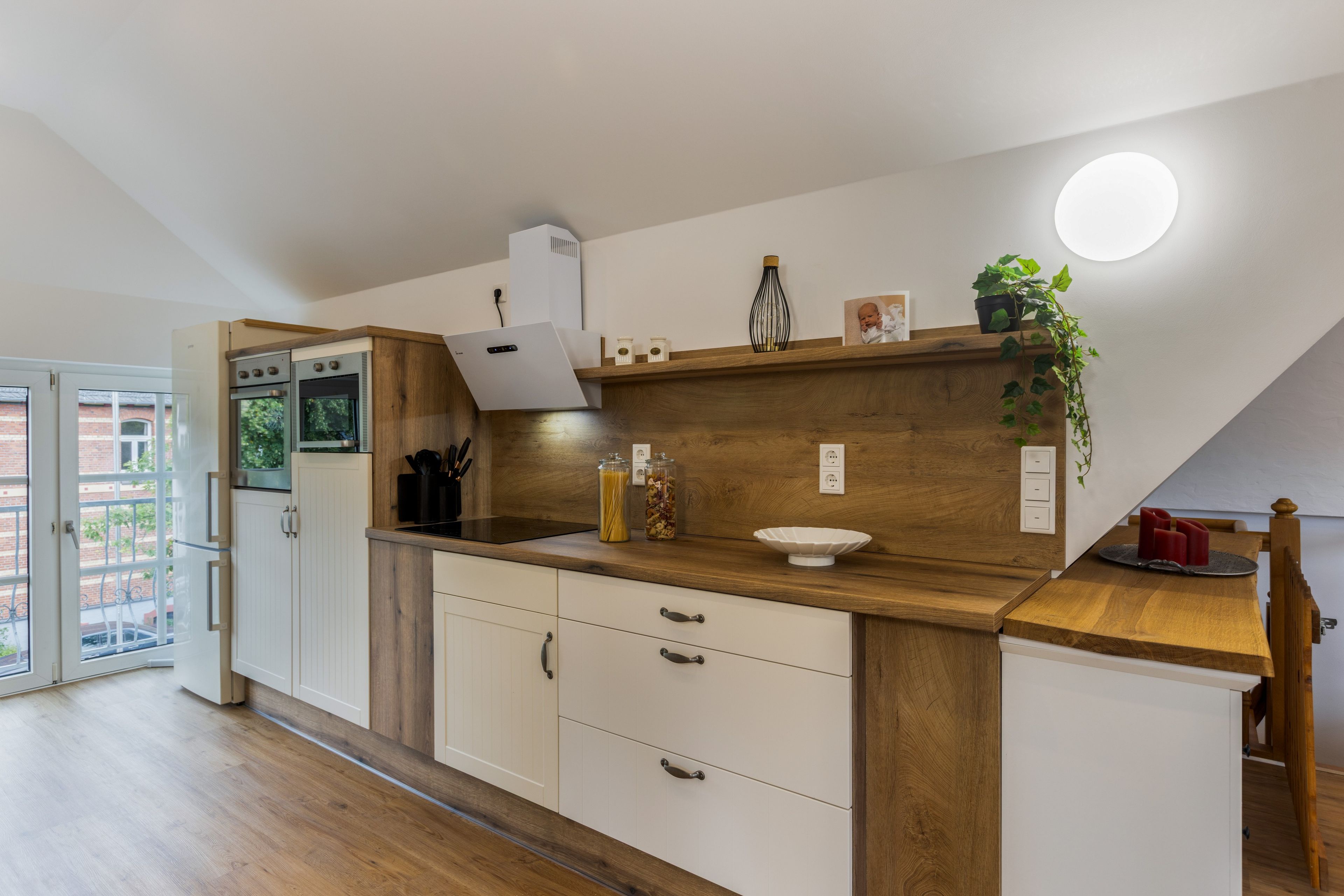 Eine moderne Küche mit Holzschränken, einem eingebauten Ofen und einer Arbeitsfläche mit verschiedenen Küchenutensilien.