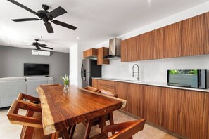 Una cucina moderna con mobili in legno, forno a incasso e televisore a schermo piatto.