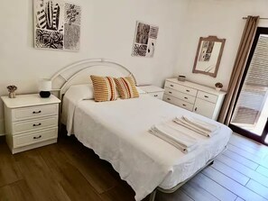 A bedroom with a bed, a nightstand, a dresser, and artwork on the walls. - A peaceful house with a swimming pool (Porches)