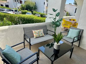 Un balcon avec un canapé, des chaises et une table sur laquelle est posée une plante en pot.