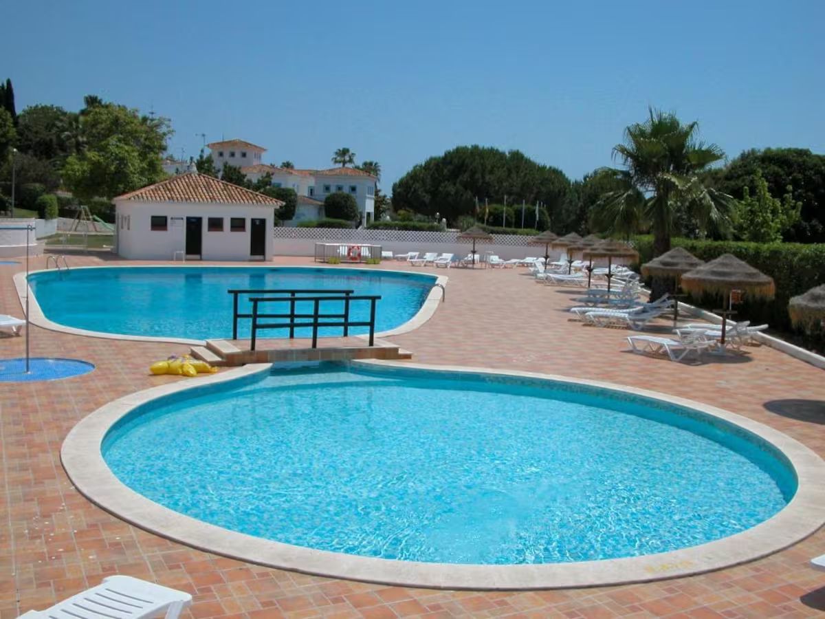 A swimming pool with a sunshade area and lounge chairs.