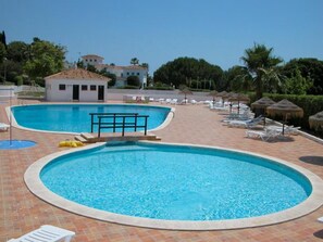 Une piscine dotée d’un espace ombragé et de chaises longues.