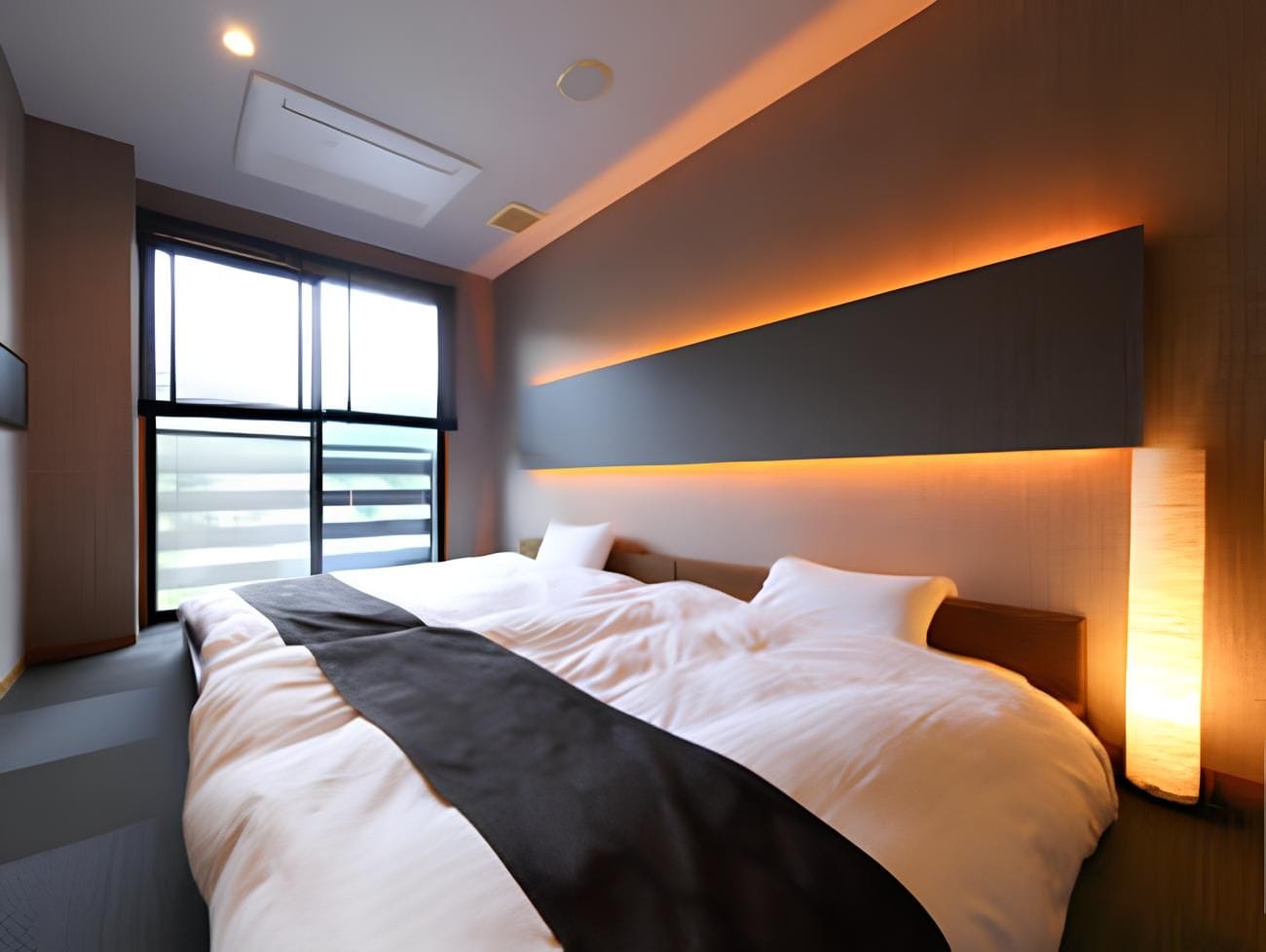 Ein modernes Hotelzimmer mit einem großen Bett, einem Fenster mit Blick und einer wandmontierten Lampe.