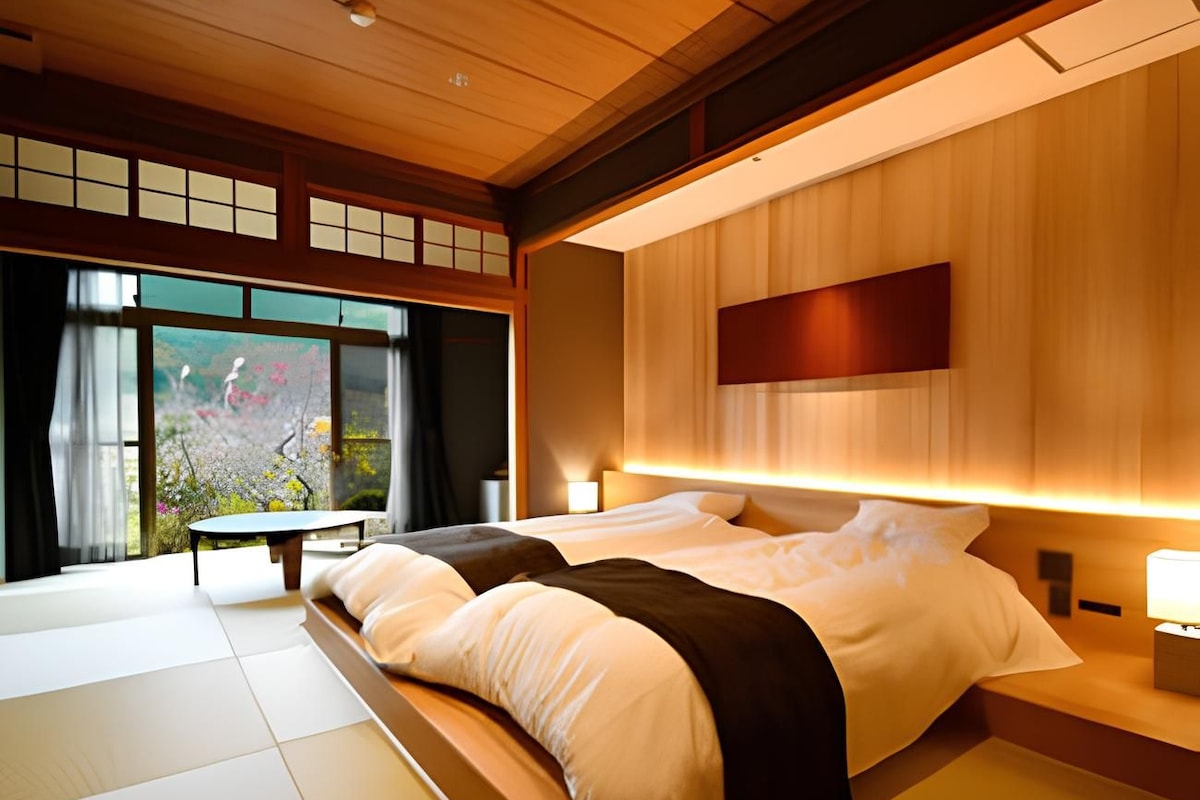 Habitación de hotel moderna con una cama grande, una mesita de noche y vistas a un jardín por la ventana.