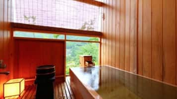 Ein Zimmer aus Holz mit einer Whirlwanne, einem Fenster und einem kleinen Holzschemel.