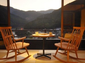 Dos mecedoras mirando a una mesa con tazas, con vista a un paisaje montañoso.