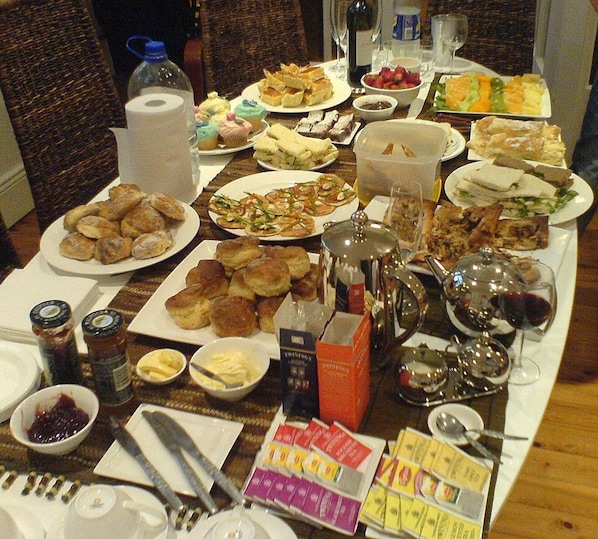 A table with various food items, condiments, and utensils, suggesting a buffet or communal meal setting. - Authentic (Šid)
