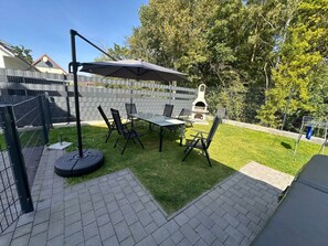 An outdoor patio with a table and chairs, a barbecue grill, and a pergola. - Villa Trisatus on the Lake (Goehren-Lebbin)