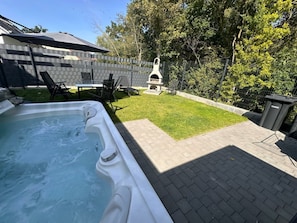 A backyard with a hot tub, a barbecue grill, and a patio area. - Villa Trisatus on the Lake (Goehren-Lebbin)