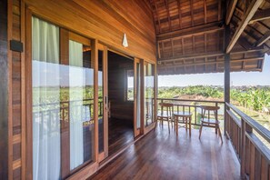 Un balcon en bois offrant une vue sur un paysage rural.