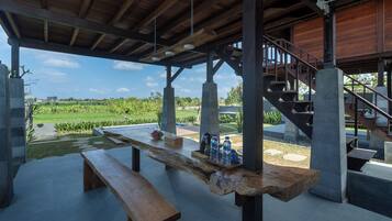 Un espacio para comer al aire libre con un banco de madera y una mesa, una escalera y vistas a un paisaje verde.