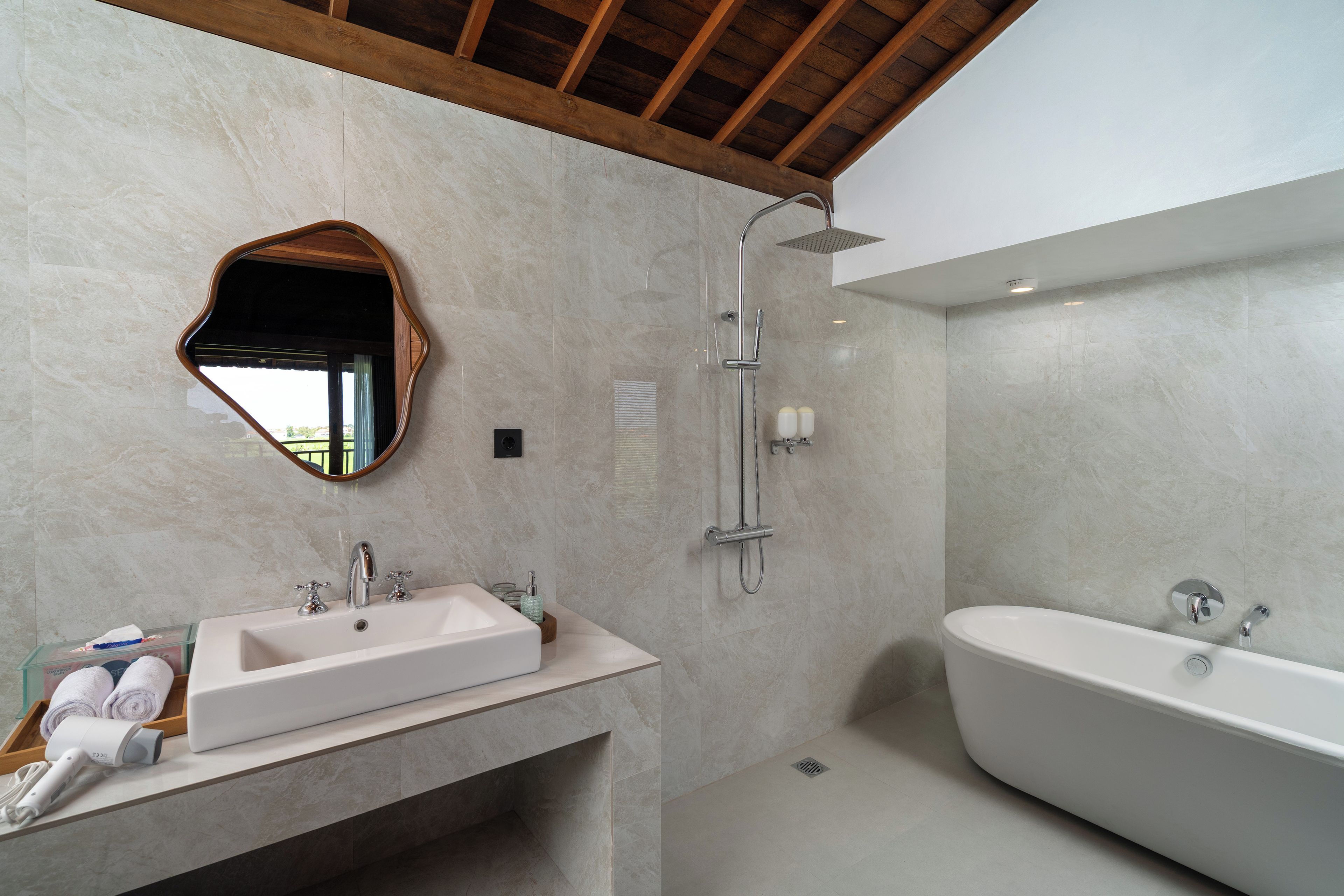 Un baño moderno con una bañera independiente, un tocador con lavamanos y una ducha con cabezal de ducha manual.
