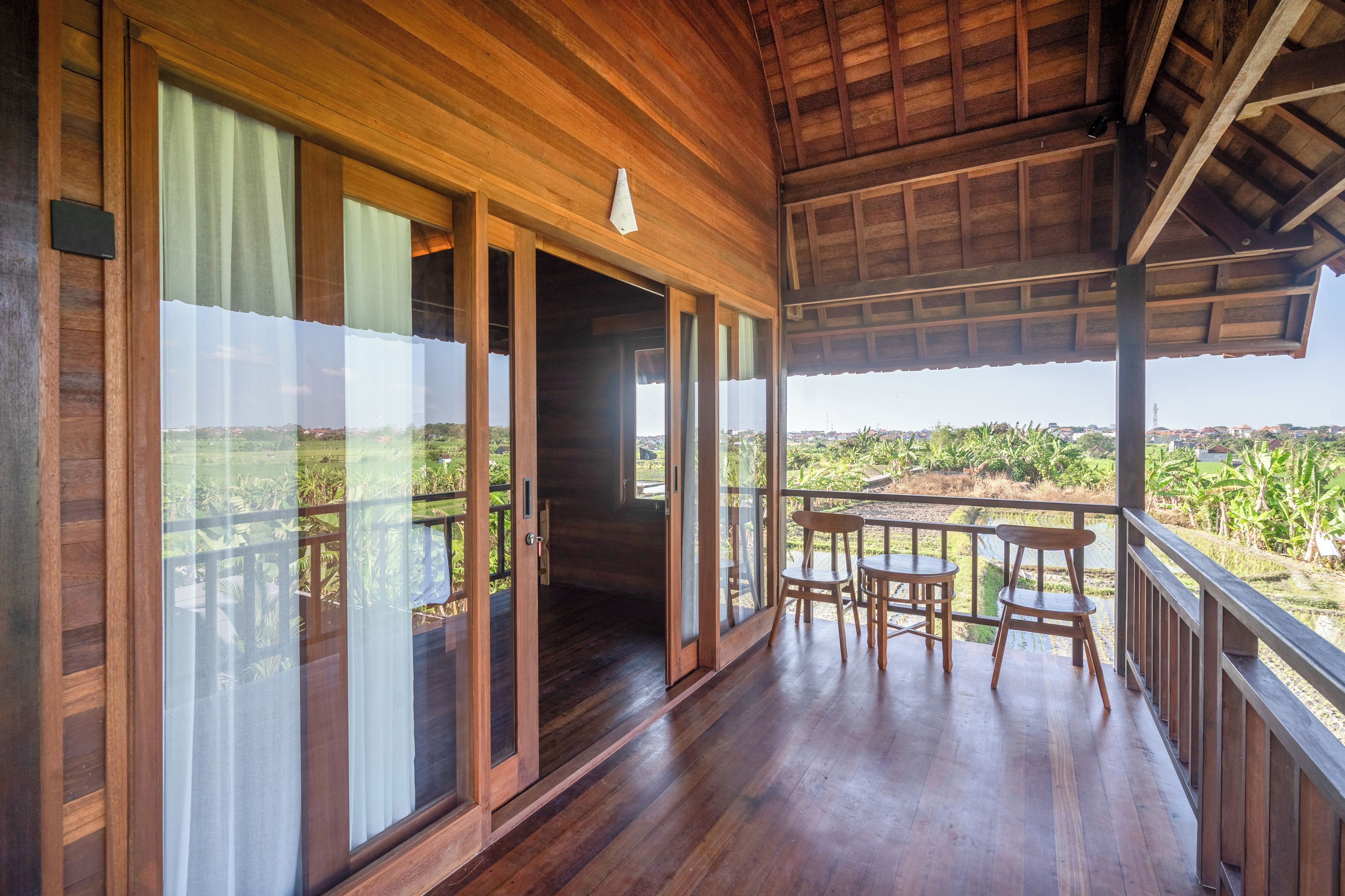 A wooden balcony with a view of a rural landscape.