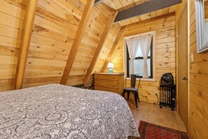 Una stanza accogliente in legno con un letto, un comodino, una sedia e una finestra con tende.