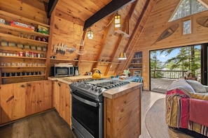 Una cocina acogedora con paredes de madera, una estufa a gas y un microondas.