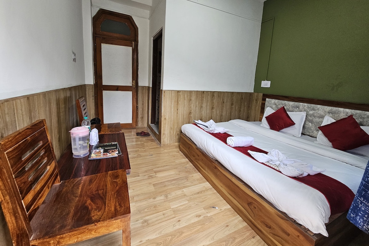 A hotel room with a wooden bed, a wooden desk, and a green wall.