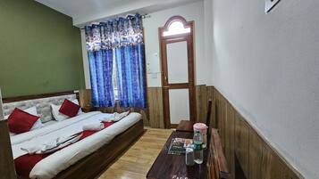 Una habitación con una cama, una mesa de madera con una botella de agua y un espejo en la pared.