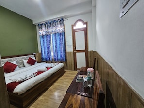 A room with a bed, a wooden table with a water bottle, and a mirror on the wall.