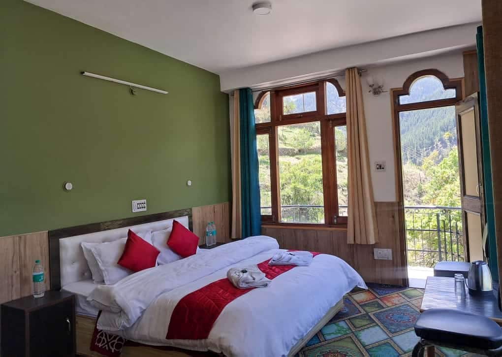 Ein Hotelzimmer mit einem Bett, einem Schreibtisch, einem Stuhl und einem Fenster mit Blick auf Grünflächen.