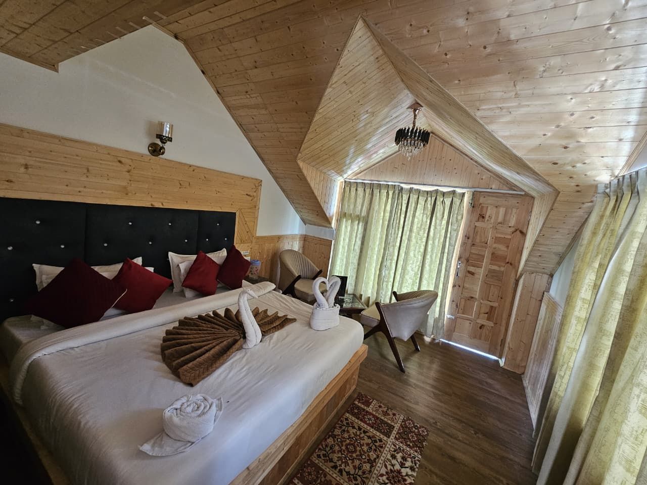 A hotel room with a large bed, wooden ceiling, and a view of the outside.